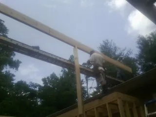 Carpenter setting a ridge beam over a new addition frame — Ice Dam Removal by Roofing Brothers in Wauneta