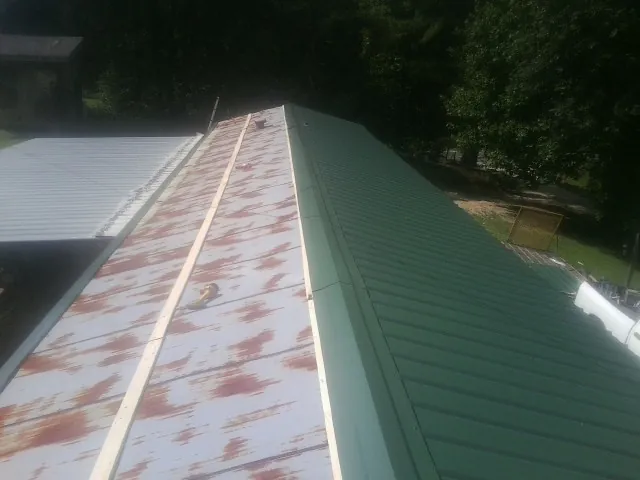 Old rusted panels beside newly installed green metal roofing — Wind Damage Roof Repair by Roofing Brothers in Wauneta