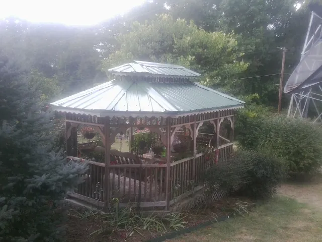 Green metal roof on a backyard gazebo surrounded by garden beds in Wauneta