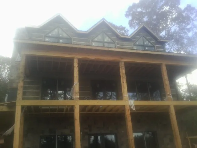 Dormers and porch framing on a large log home under construction — Roof Coating work by our crew in Wauneta