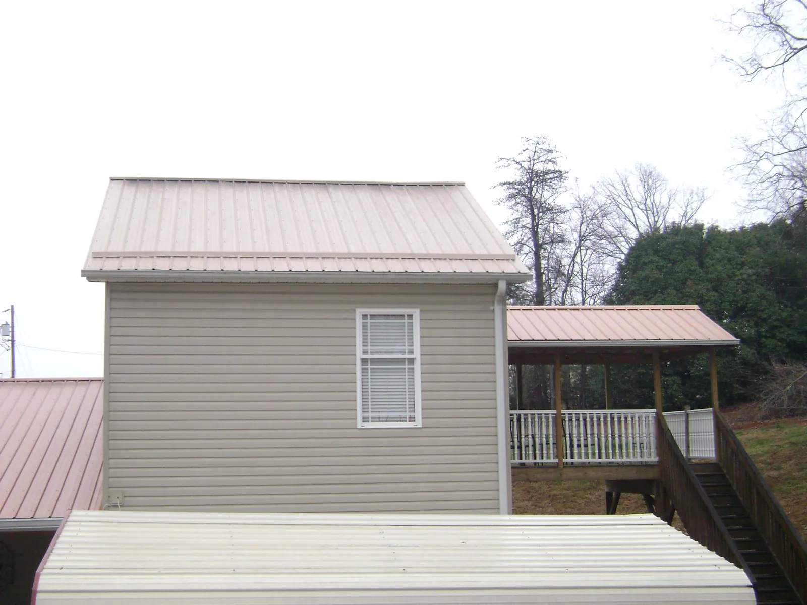 Tan metal roofs on a two story addition and attached porch, from a Roof Replacement job in Wauneta