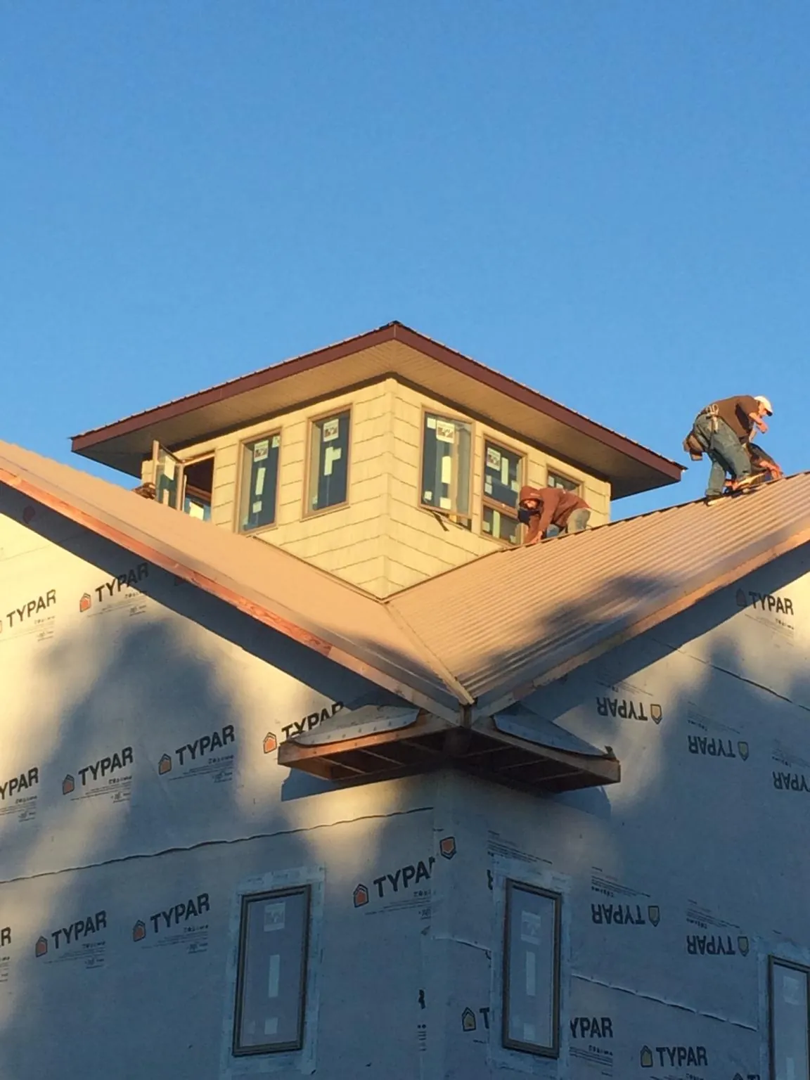 Roofers working around a rooftop cupola on a new metal roof at sunset — Roof Waterproofing in Wauneta by Roofing Brothers